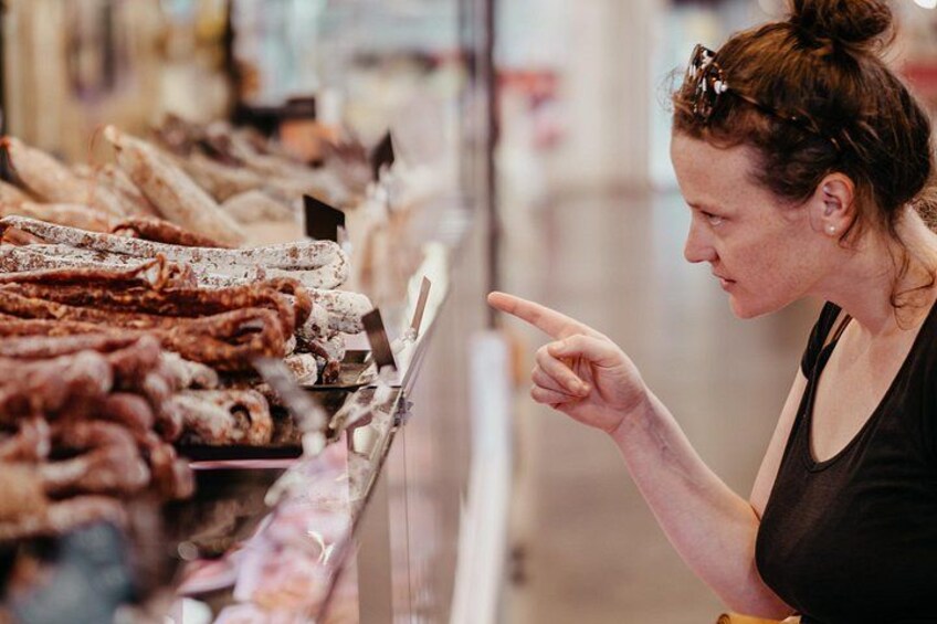 A person pointing at a display of various food items in a store. 4