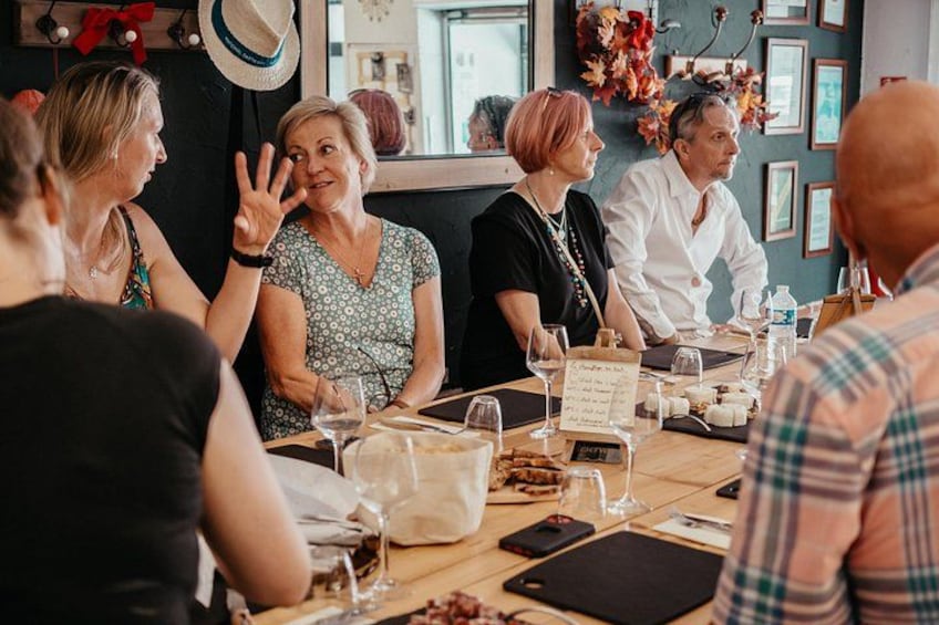 A group of people seated at a table with wine glasses, a menu, and a laptop. 3