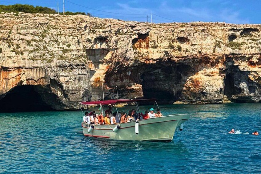 A boat with passengers near a rocky coastline and a cave entrance. 5