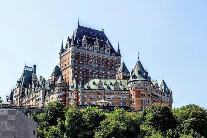 A large, historic building with multiple towers and spires, surrounded by lush green trees. 2