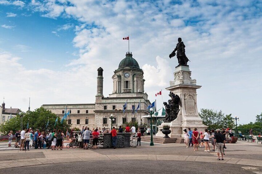 Une place publique avec un grand bâtiment, une statue et des gens. 3