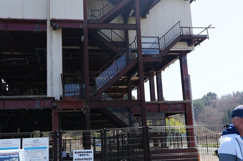 A multi-story building with a metal staircase and a fenced area. 3