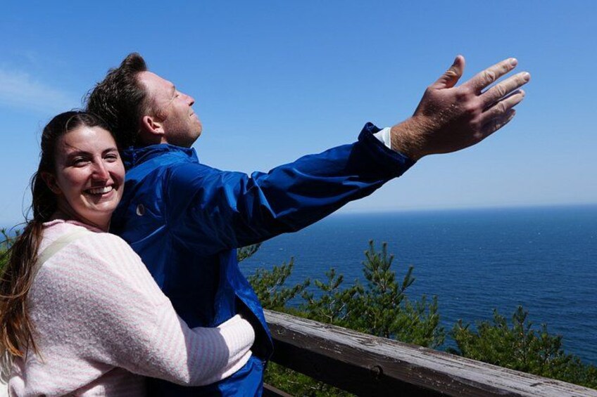 A person in a blue jacket extending their arm towards the ocean. 1