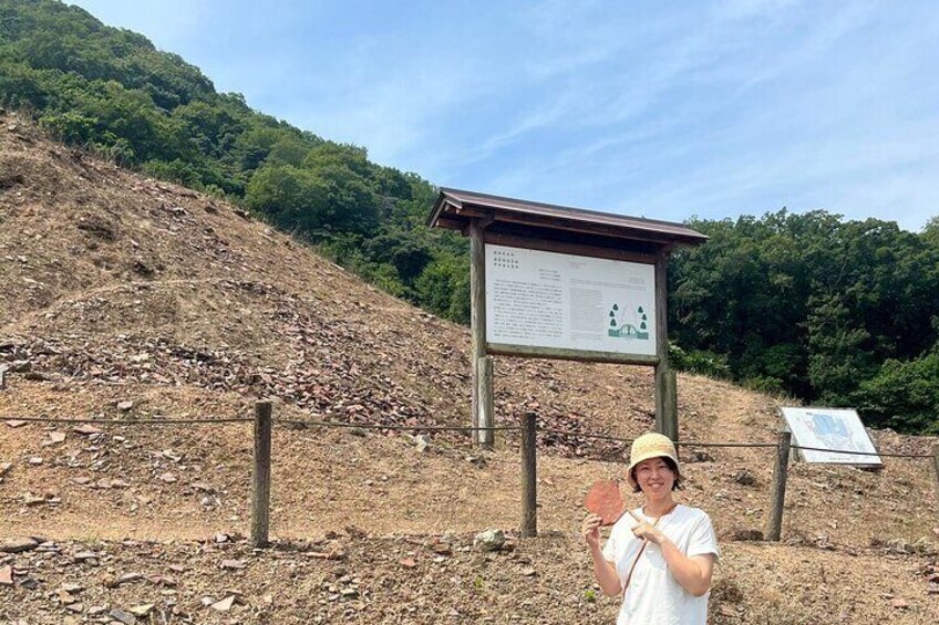 A person standing in front of a signpost on a hillside with a forested background. 3
