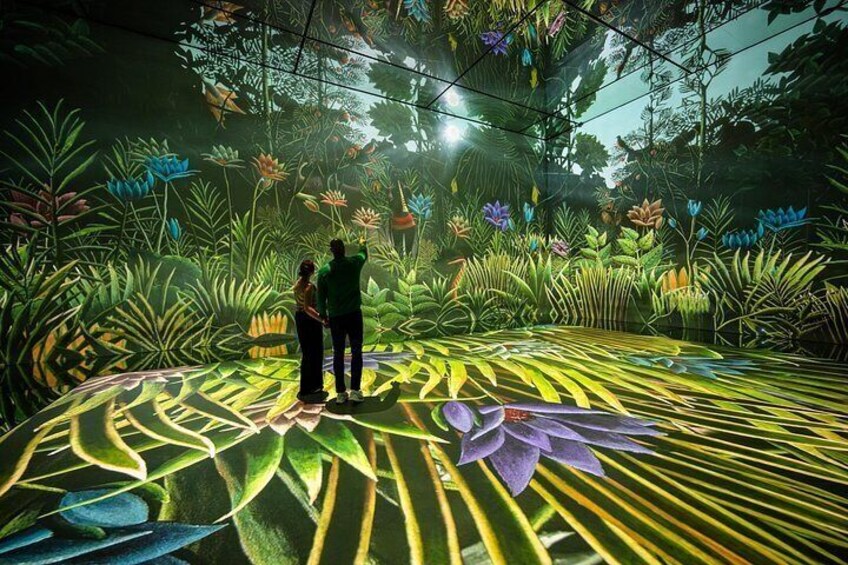 A couple standing on a patterned floor with a large purple flower in the foreground. 4