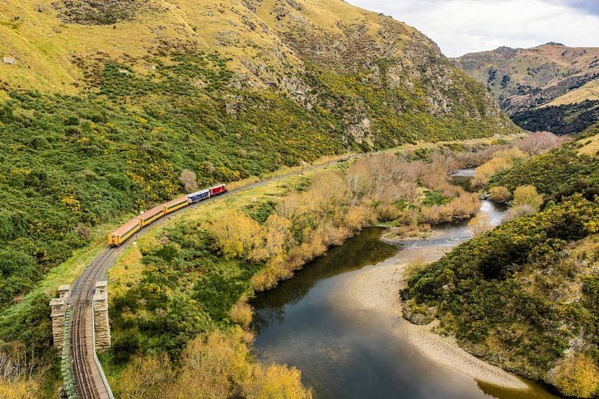 Un train circule sur une voie ferrée qui traverse un paysage montagneux, avec une rivière. 3