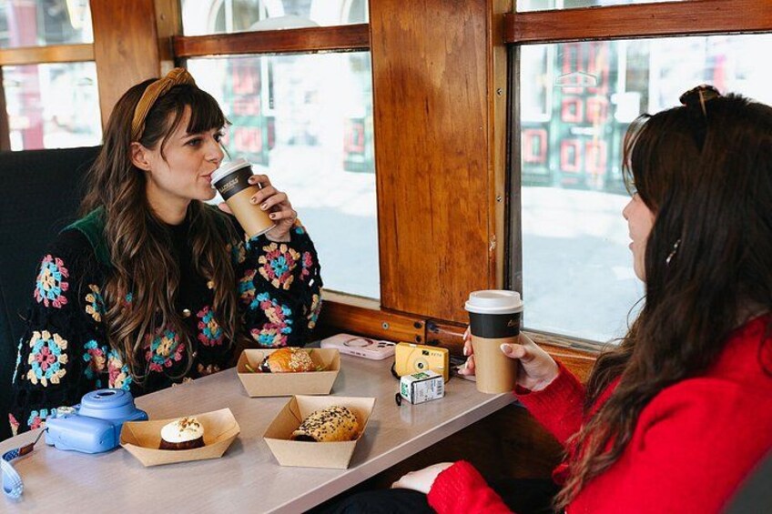 Dos personas sentadas a una mesa con tazas de café y bollería. 4