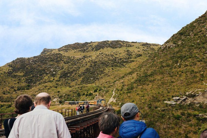 A group of people on a bridge overlooking a mountainous landscape. 3