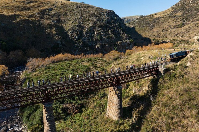 Un tren cruzando un puente sobre un río, rodeado de colinas y vegetación. 2