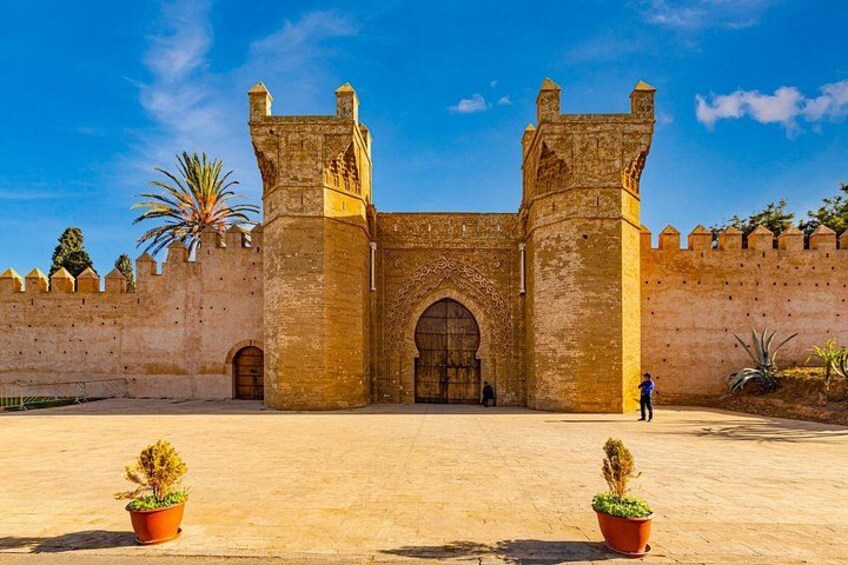 A historic walled building with arched gateways and a person standing in the foreground. 5