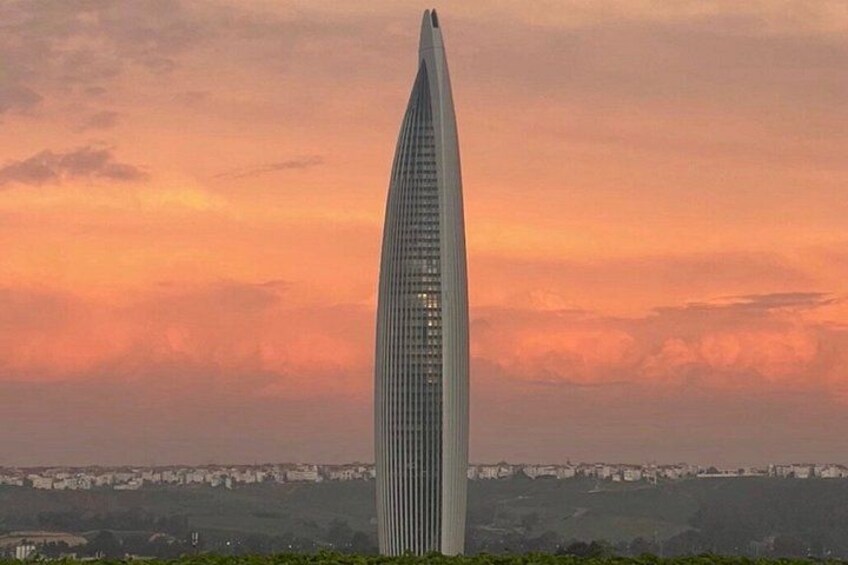 A tall, slender skyscraper with a pointed top, set against a sunset sky. 3