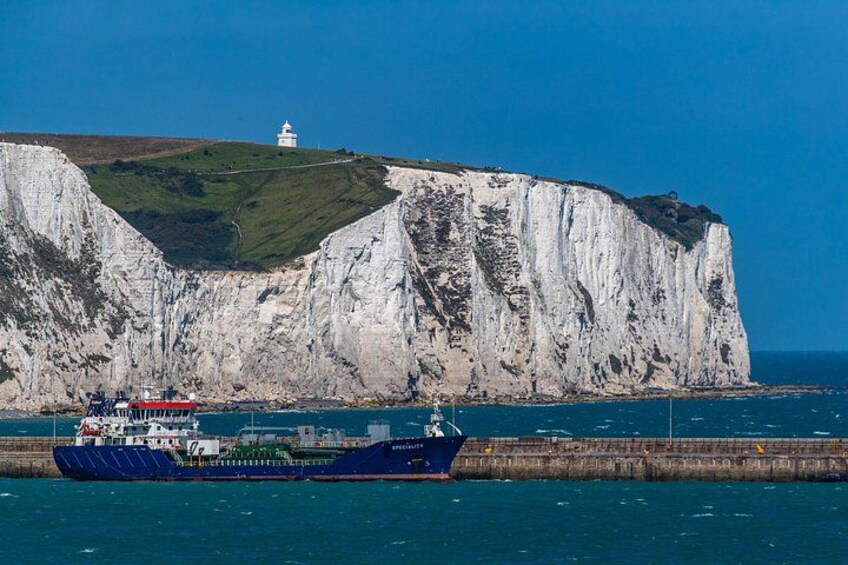 A large ship near a cliff with a lighthouse on top. 3