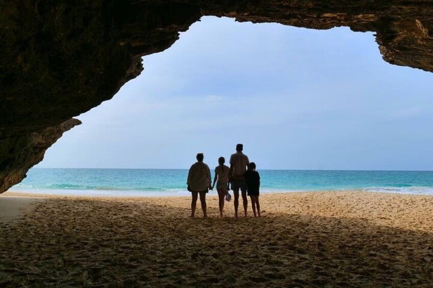 A family standing in a cave opening on a beach. 3