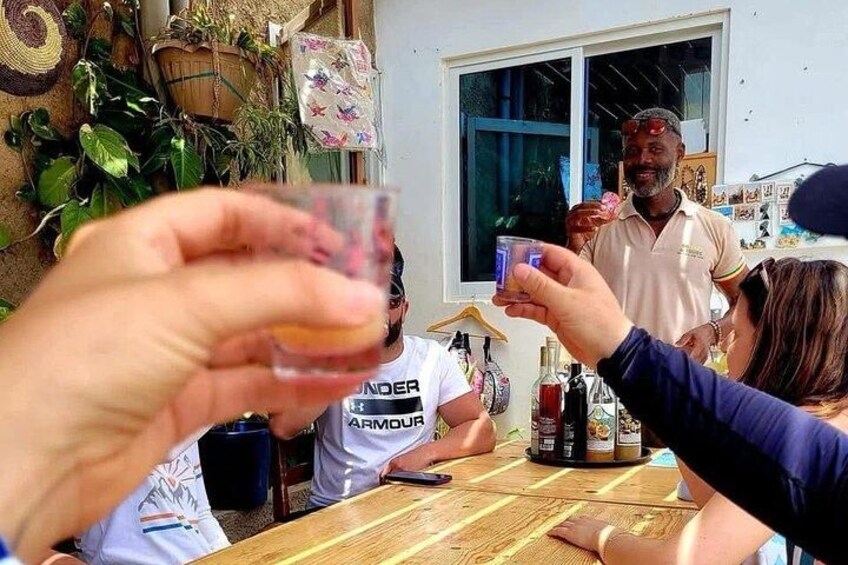 A group of people sitting at a wooden table outdoors, holding glasses of a beverage. 2