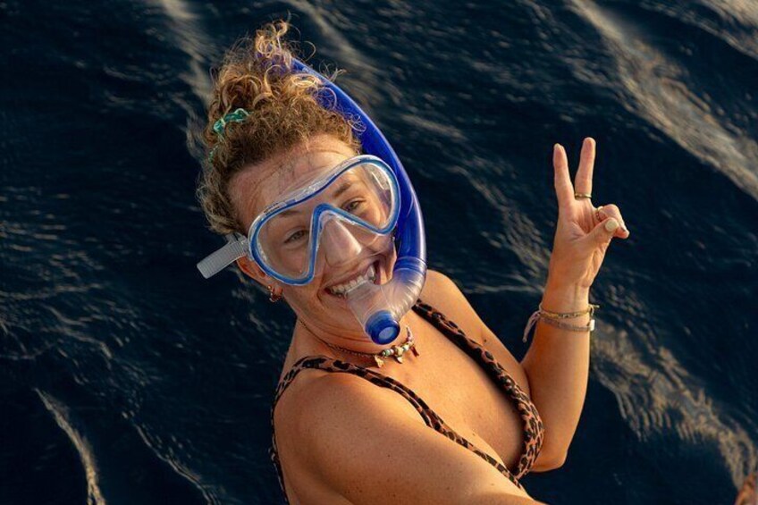 A person snorkeling with a blue mask and snorkel, making a peace sign. 5