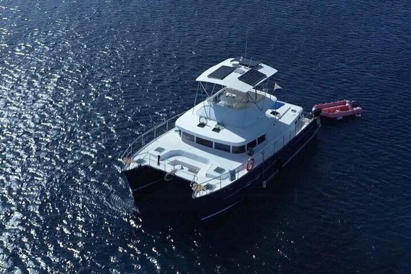 A large white boat with a red lifeboat docked at its stern, floating on calm water. 3