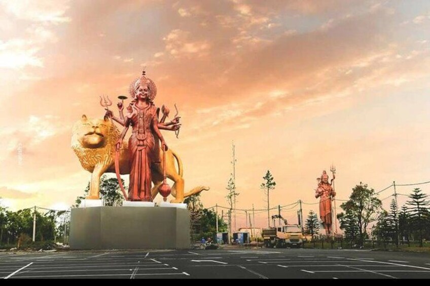 Una gran estatua de una deidad sobre un león, con un atardecer de fondo. 3