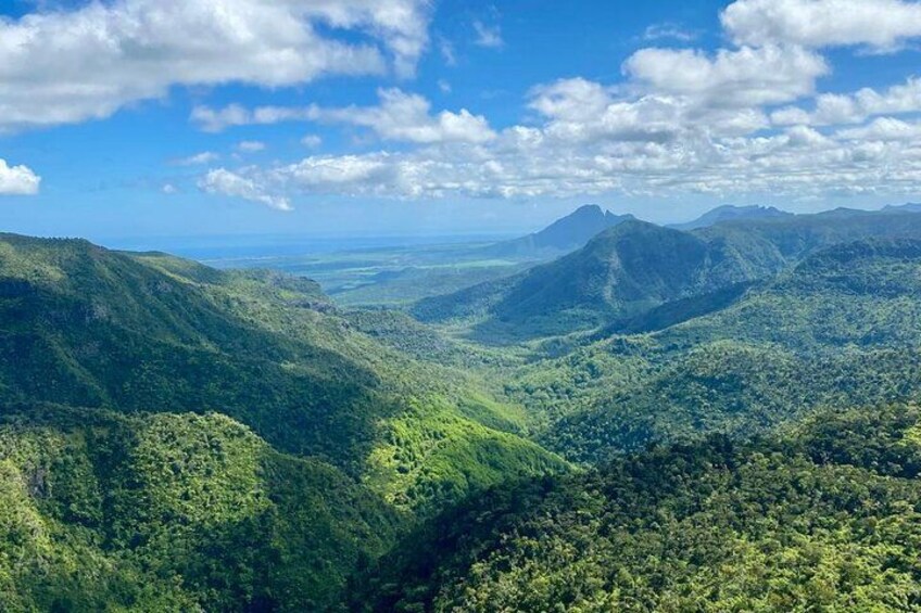 Un paisaje montañoso con densos bosques verdes y un cielo azul despejado. 2