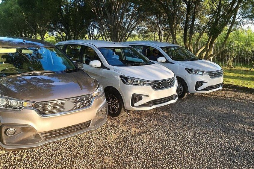 Three cars parked on a gravel surface with trees in the background. 2