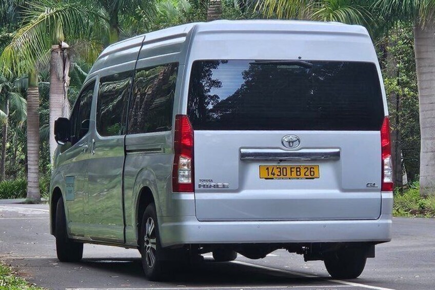 Un fourgon Toyota argenté est garé sur une route, avec des palmiers en arrière-plan. 3