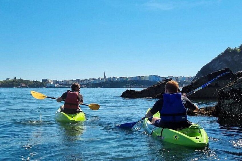 Deux personnes pratiquent le kayak sur une étendue d’eau calme, avec une vue sur les bâtiments d’une ville en arrière-plan. 3