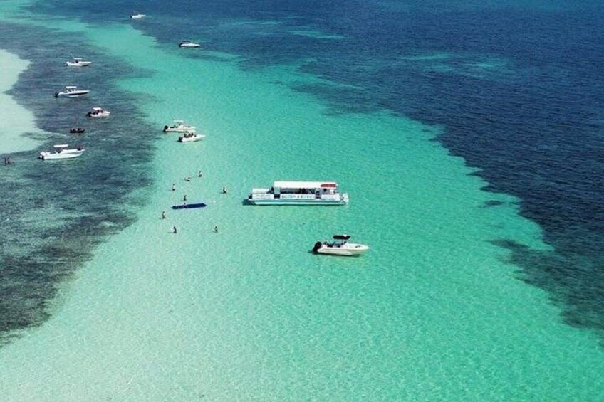 An aerial view of a turquoise sea with boats and a large cruise ship. 3