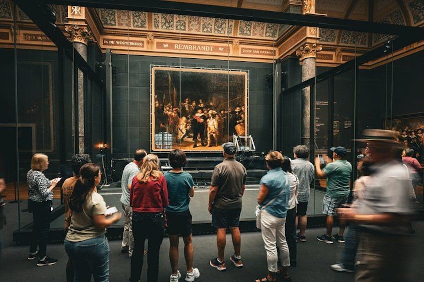 En grupp människor som betraktar en stor målning på ett museum. 5