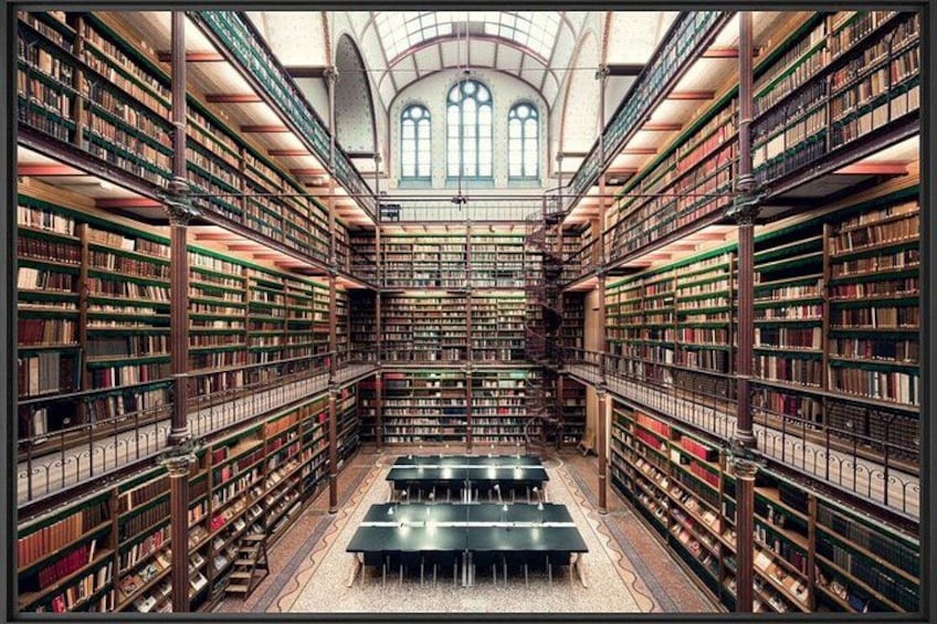 Ett stort, utsmyckat bibliotek med höga bokhyllor och en central läsplats. 2