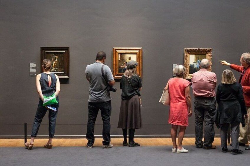 A group of people observing paintings in a gallery. 3