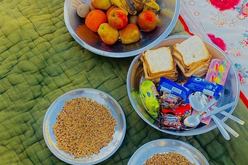 Montaje para picnic con tazones de frutas, pan, bocadillos y granos sobre una superficie acolchada verde. 5