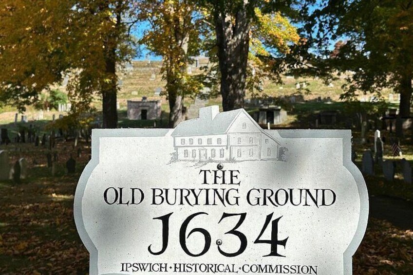 A gravestone with a house illustration and the text 'The Old Burying Ground J634' and 'Ipswich Historical Commission'. 2