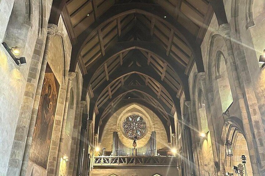 A cathedral interior with a large circular stained glass window, arched ceilings, and stone walls. 3