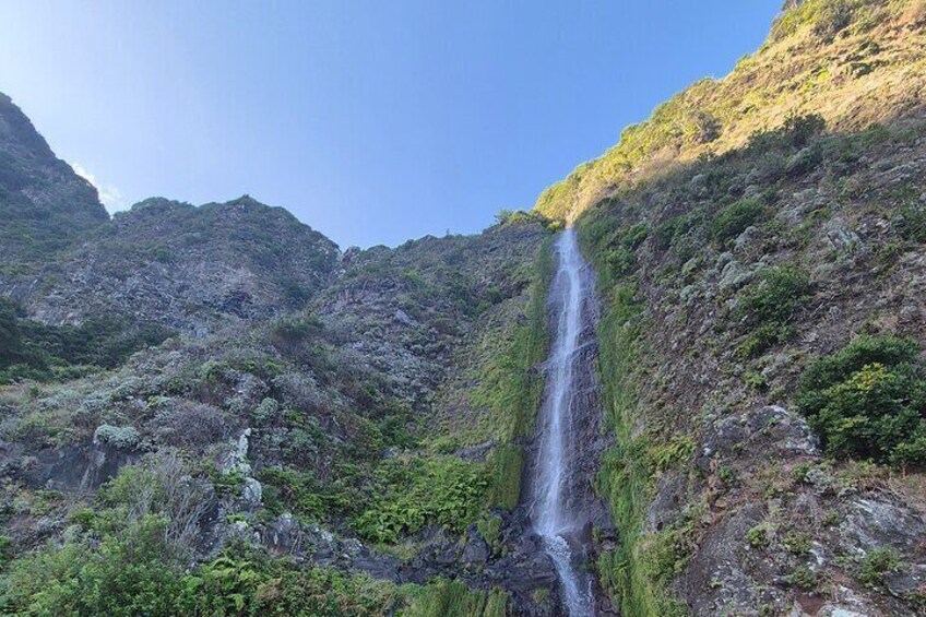 Una cascata che si getta da una parete rocciosa, circondata da una vegetazione rigogliosa. 2