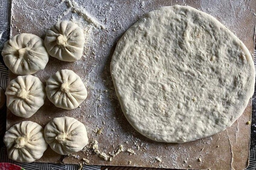 Dough on a floured surface with several dumplings and a large piece of dough. 3