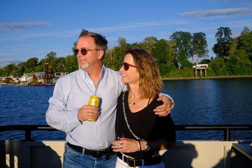 Two people standing by a waterfront with a body of water and greenery in the background. 2