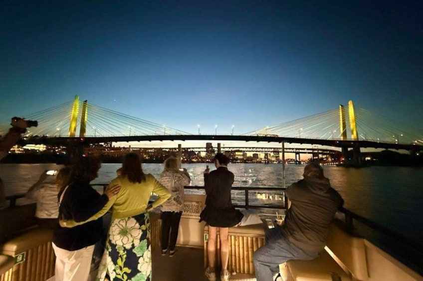 A group of people on a boat, a bridge, and a body of water. 2
