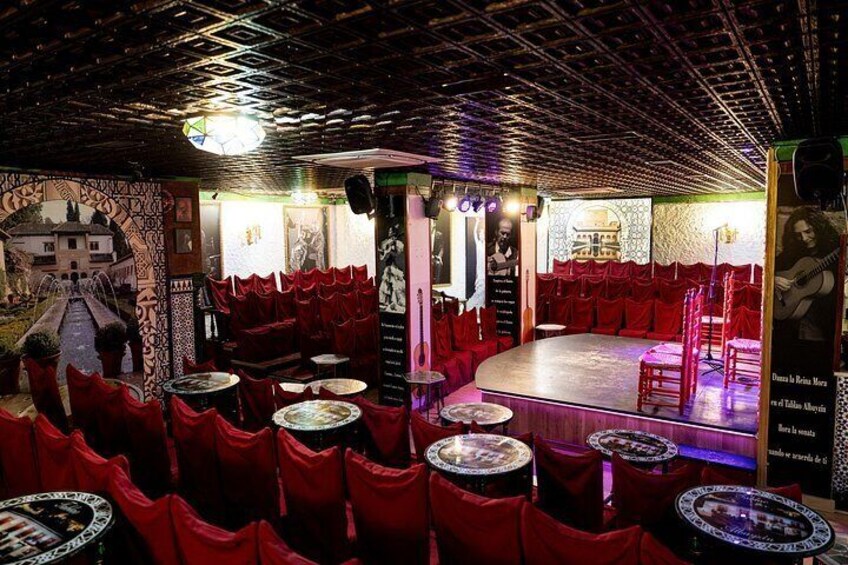 Un restaurante con sillas rojas, un escenario y un mural. 4