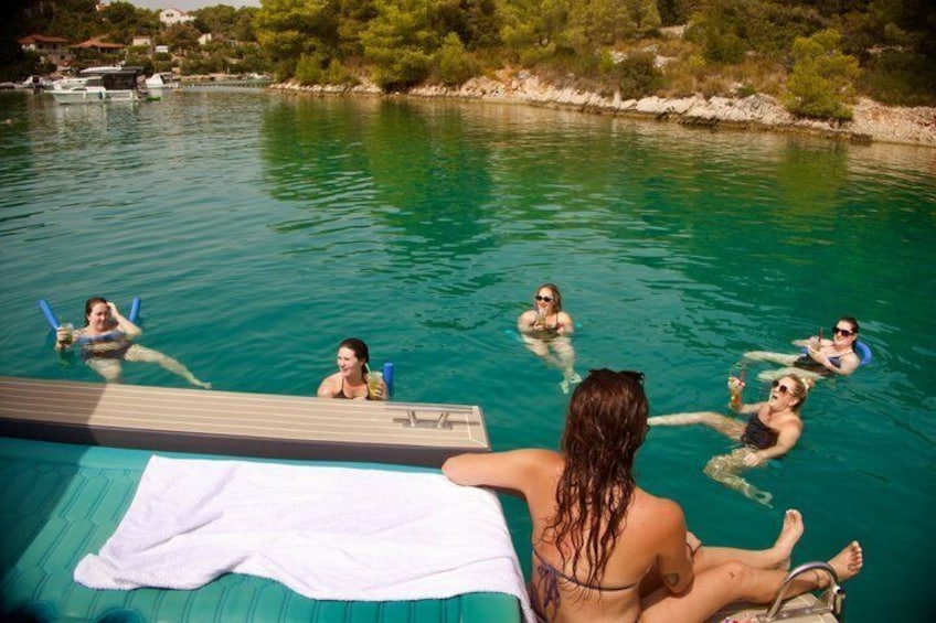 A swimming pool with people enjoying the water, a towel on the deck, and a boat in the background. 4