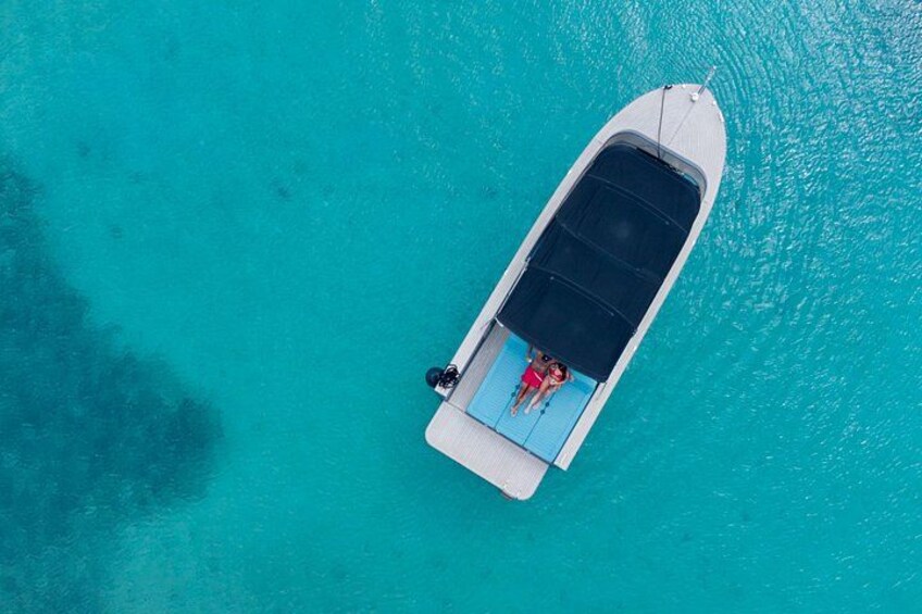 An aerial view of a boat with two people on a turquoise sea. 5