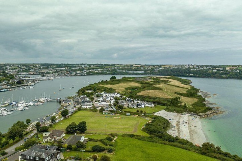 A coastal town with a marina, sandy beach, and green hills. 2