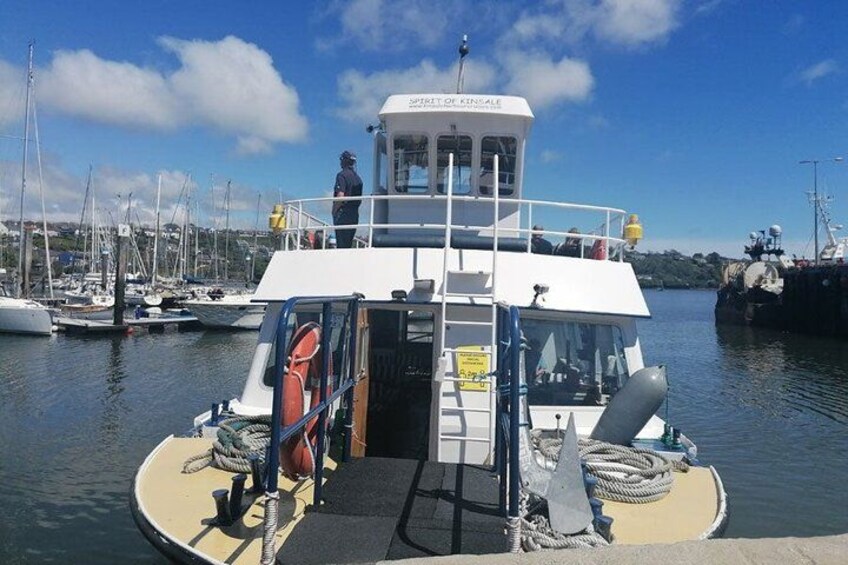 A boat docked at a marina with a person standing on the deck, a lifebuoy, ropes, and a sign. 2