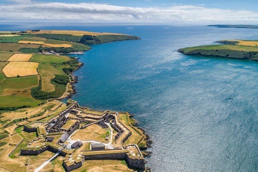 An aerial view of a coastal fortification with surrounding agricultural fields and a clear blue sea. 3
