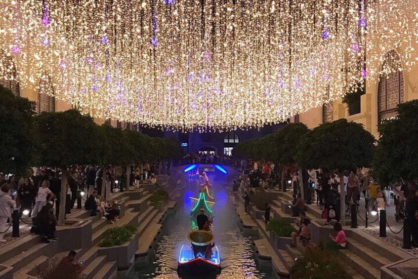 Un espacio exterior festivo con fuente de agua, decoraciones iluminadas y una multitud de personas. 2