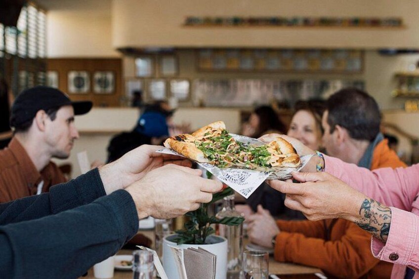 Guests dig into Vietnamese-Thai fusion pizza at Sing Sing, a lively Mount Pleasant hotspot blending street food soul with craft beer charm. 2
