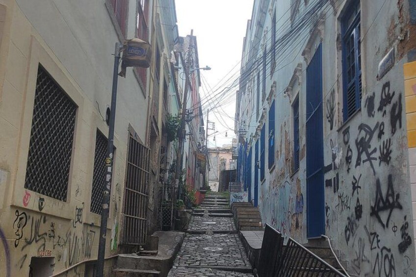 Un stretto vicolo fiancheggiato da edifici, alcuni con graffiti e altri con persiane blu. 4