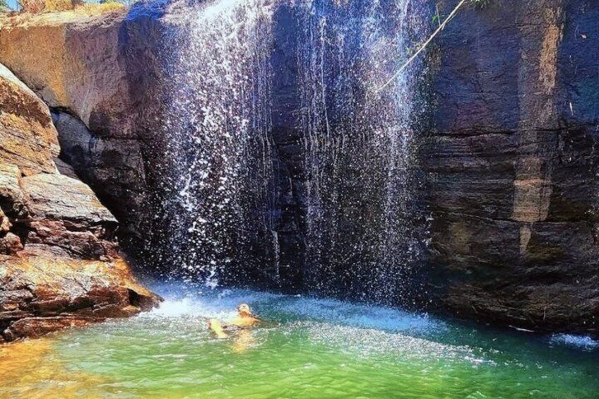 Ein Wasserfall stürzt in einen Pool klaren Wassers neben steilen Felsen. 2