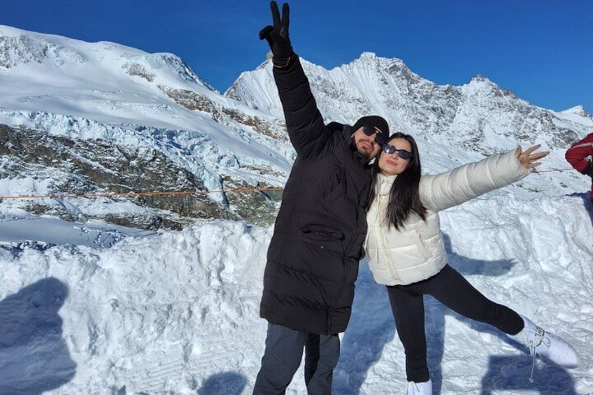 Deux personnes posent devant un paysage de montagnes enneigées. 2