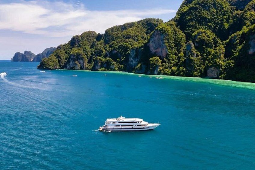 Un yacht blanc sur des eaux turquoise, avec des falaises verdoyantes en arrière-plan. 3