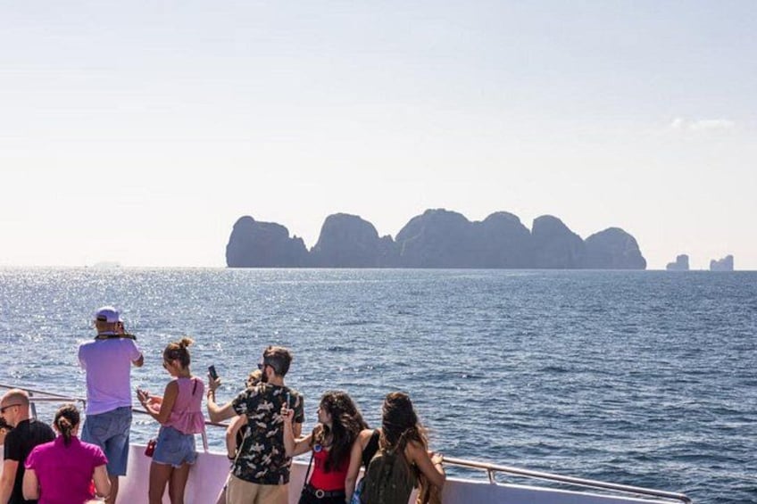 Un grupo de personas en un bote, mirando un mar tranquilo con formaciones rocosas a la distancia. 4