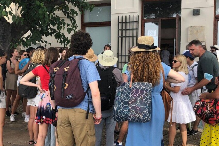 A group of people standing in line outside a building. 2